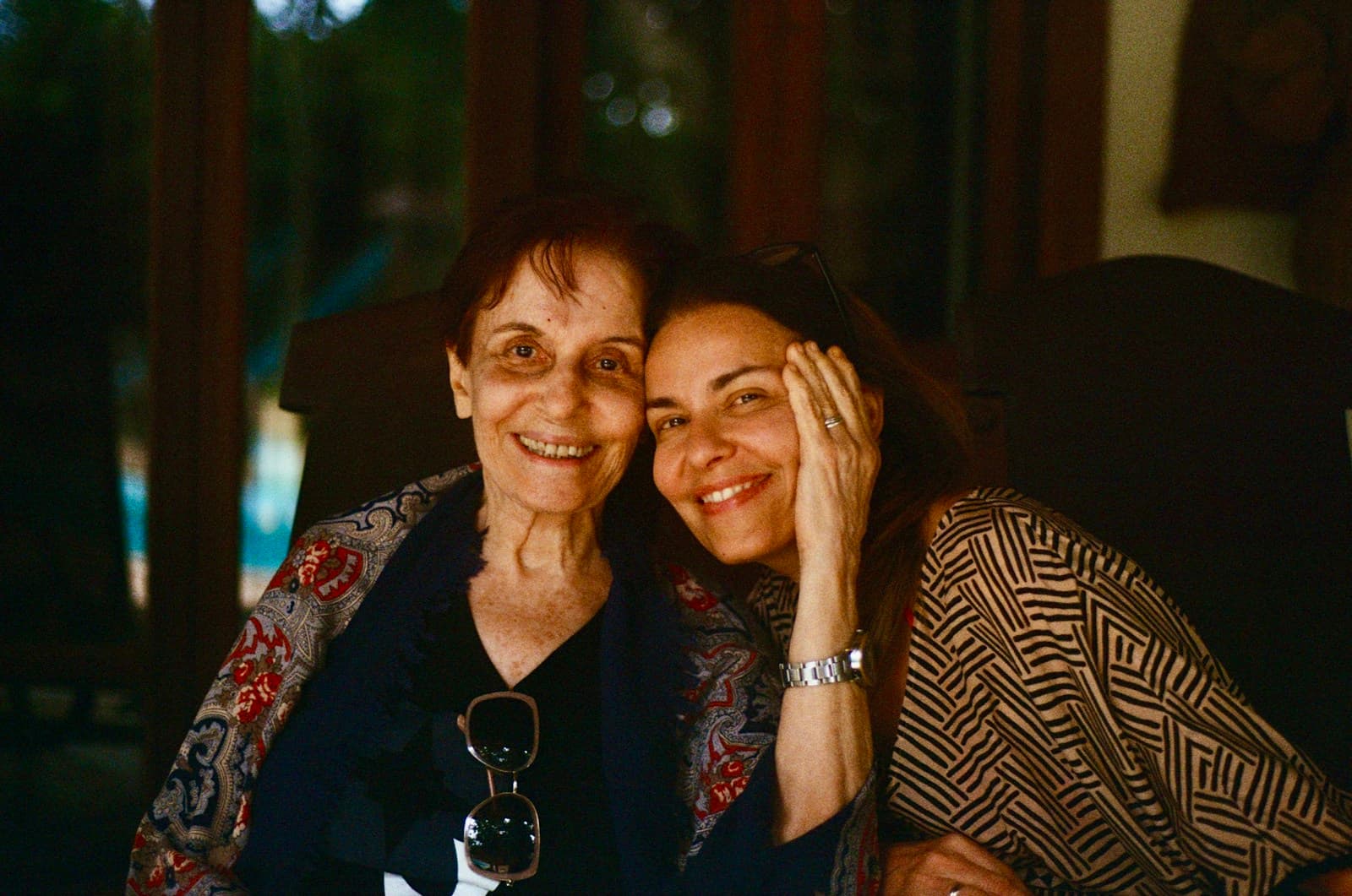 An older mother and her adult daughter smiling together